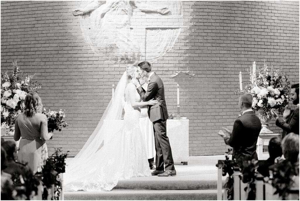 bride and groom share first kiss at wedding ceremony inside church