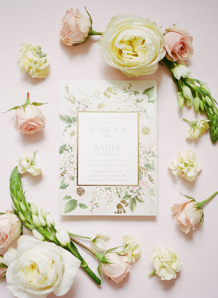 Wedding invitation flat lay with blush and ivory flowers