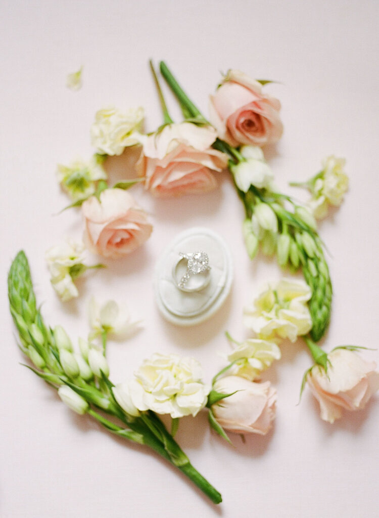 Engagement ring in box surrounded by blush and ivory flowers