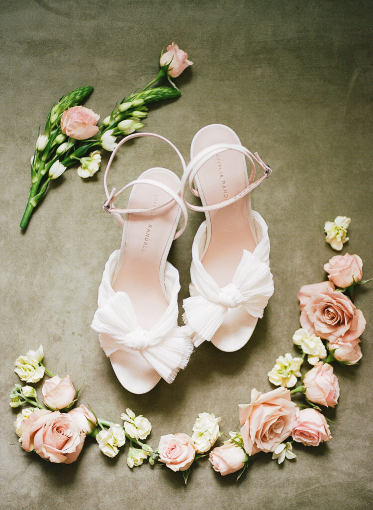 Bride's white Loeffler Randall bow heels surround by blush and ivory flowers