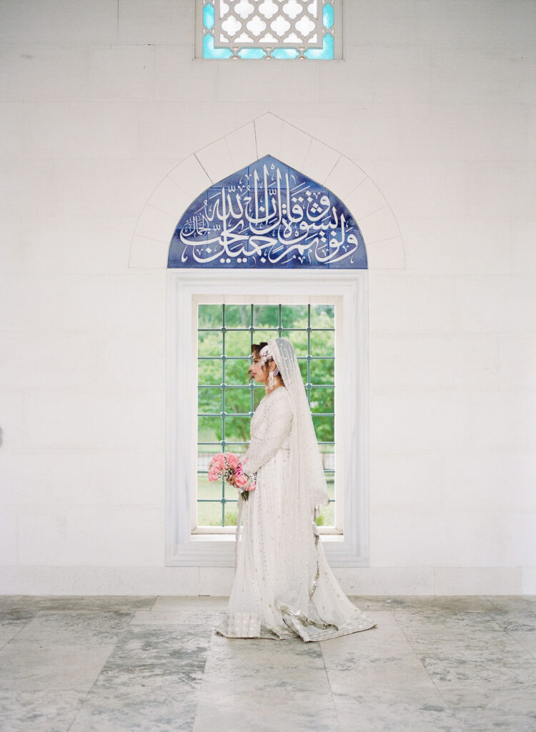Bride in Indian wedding gown walking past a window