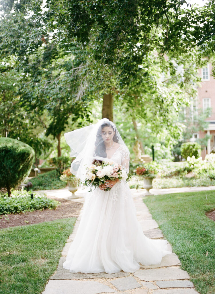 Bride in a lace and tulle gown walking down the aisle outside at Meridian House