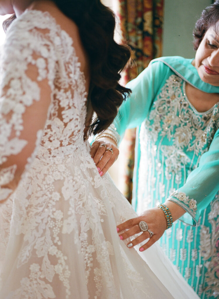 Mother of the bride helping the bride into her wedding gown