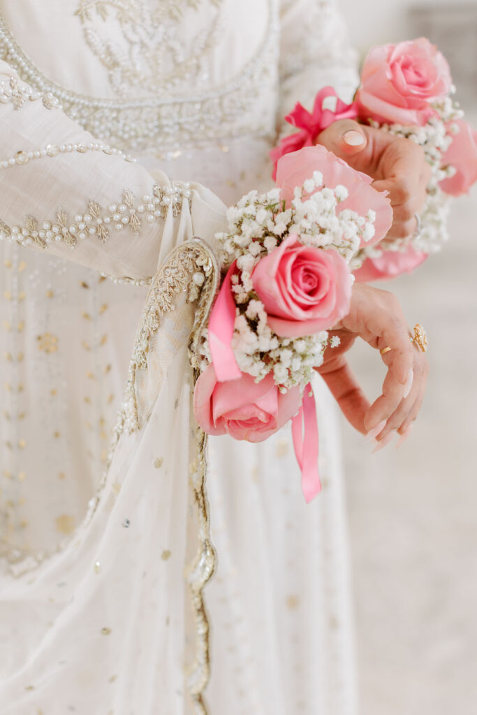 Close up of pink roses and baby's breath flowers on bride's wrists