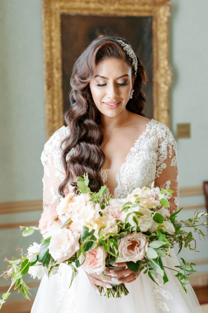 Bride holding bouquet of blush and ivory flowers in a lace gown at Meridian House